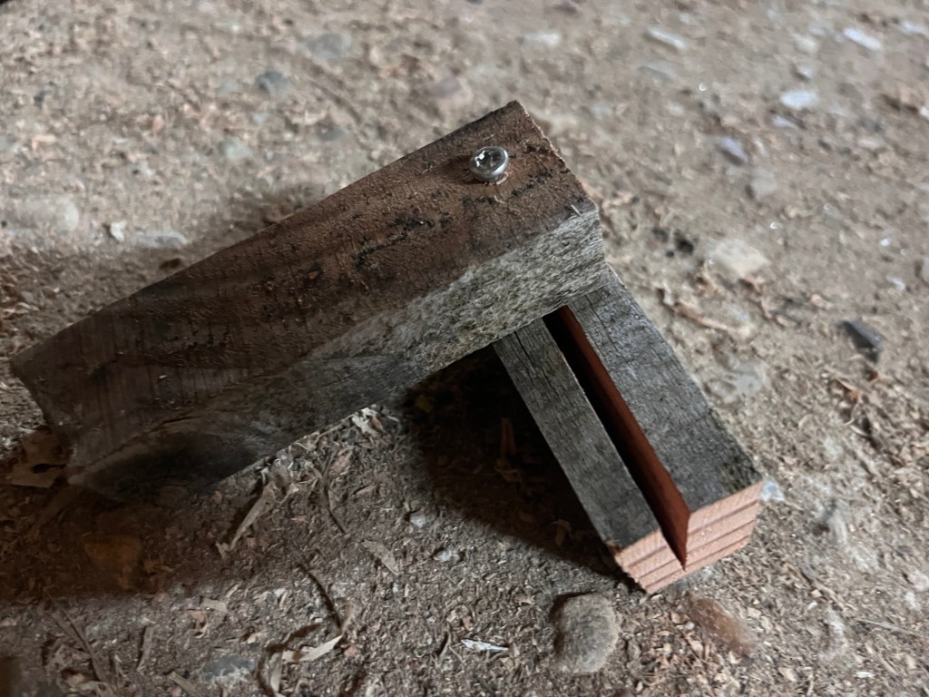 A failed test of screwing a screw through one piece of wood into another. The second piece as split open 