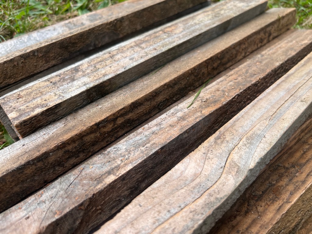 A close up showing a few still dirty pieces of wood next to some lightly sanded ones. They just look a bit cleaner, not fancy or really smooth 